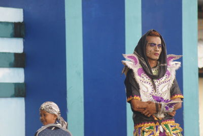Portrait of woman standing against blue wall