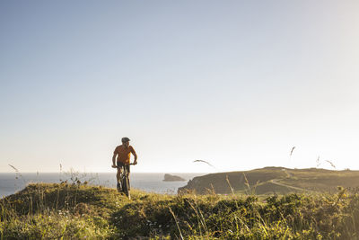 Mature sportsman riding mountain bike on green grass