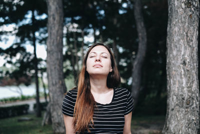 Woman with eyes closed against trees