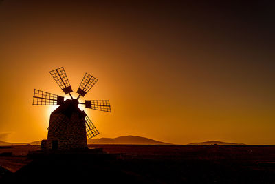 Silhouette traditional windmill against sky during sunset