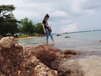 Full length of young woman on rock at beach