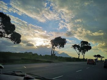 Cars on road against sky during sunset