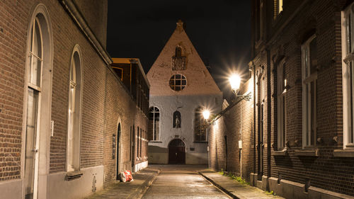 Illuminated street amidst buildings at night