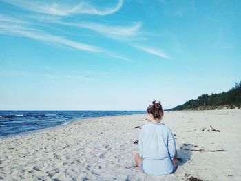 Rear view of woman sitting at beach