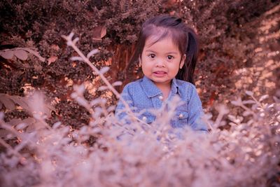 Portrait of cute girl standing amidst plants