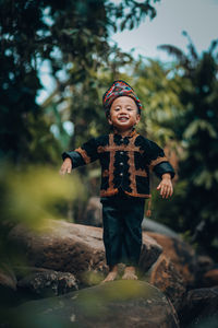 Happy boy standing against trees