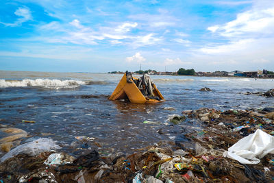 Garbage on beach by sea against sky