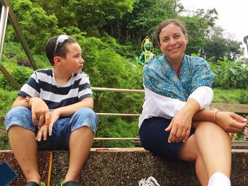 Portrait of smiling mother sitting by son in park