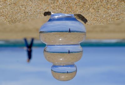 Upside down image of glass at sandy beach