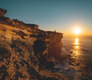 Rock formations in sea against sky during sunset