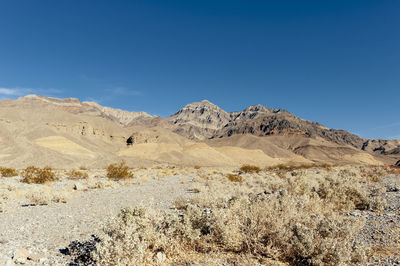 Scenic view of arid landscape against clear blue sky
