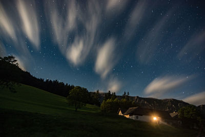 Low angle view of illuminated house against star field at night