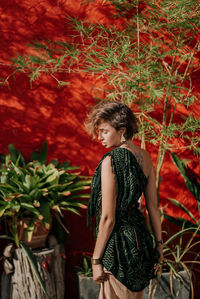 Portrait of a young woman in a green dress against a red wall