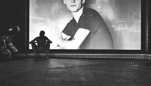 Man sitting against illuminated billboard