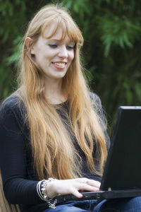 Young woman with blond hair using laptop