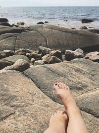 Low section of person on rocks at beach