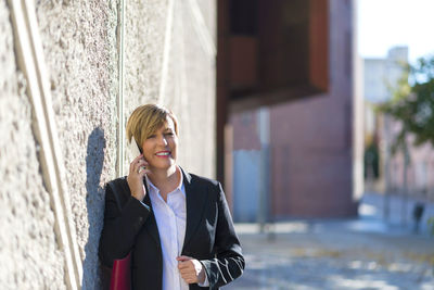 Portrait of young woman standing against building