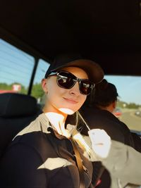 Portrait of woman wearing sunglasses while standing in car