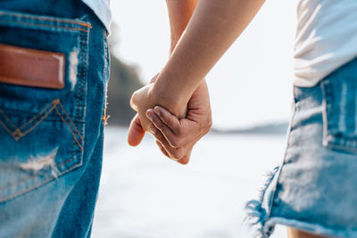 Midsection of couple holding hands