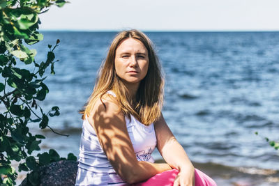 Portrait of woman sitting against sea