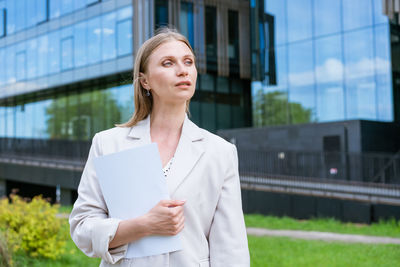 Young woman looking away while standing outdoors