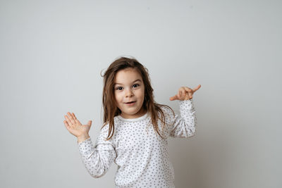 Portrait of smiling girl gesturing against white background