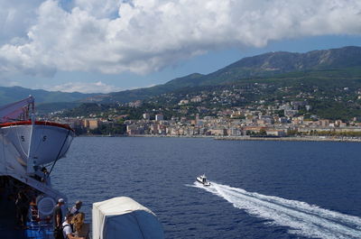 Sailboats in sea by city against sky