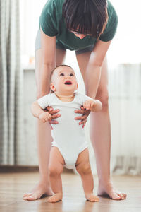 9-months old baby makes first attempts to walk. mother and son play together. family life.