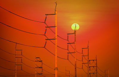 Low angle view of electricity pylon against sky during sunset