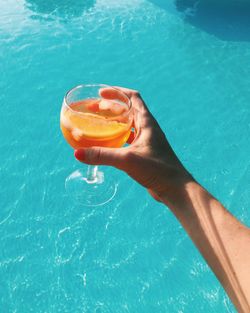 Close-up of hand holding drink in swimming pool