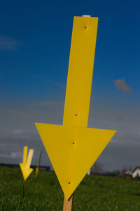 Close-up of yellow road sign against sky