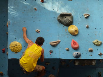 Rear view of man climbing on wall