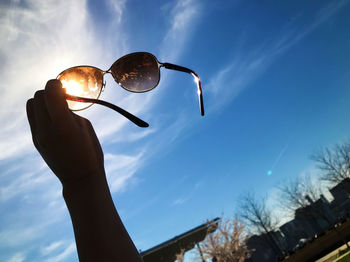 Close-up of hand holding umbrella against sky