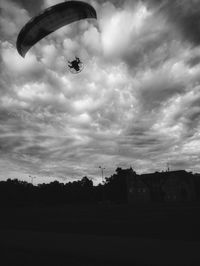 Low angle view of silhouette person paragliding against sky