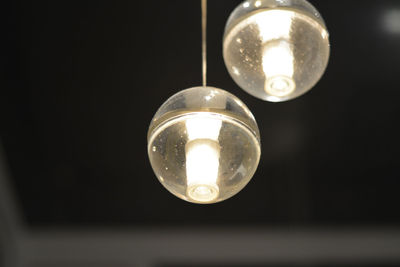 Low angle view of illuminated light bulbs hanging on ceiling
