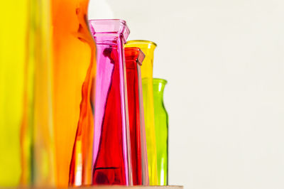Close-up of multi colored bottles against yellow background