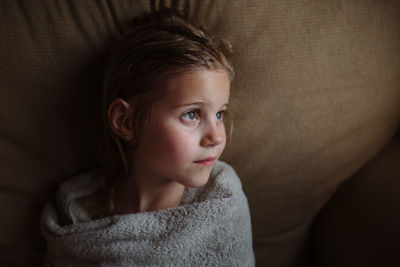 Little girl wrapped in towel after a bath looking away