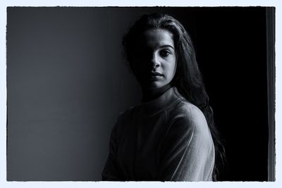 Portrait of young woman against black background