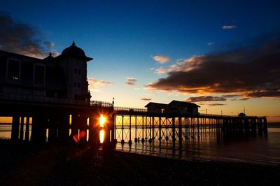 Silhouette built structure by sea against sky during sunset