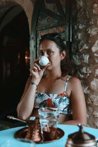 Portrait of woman drinking coffee while sitting in cafe
