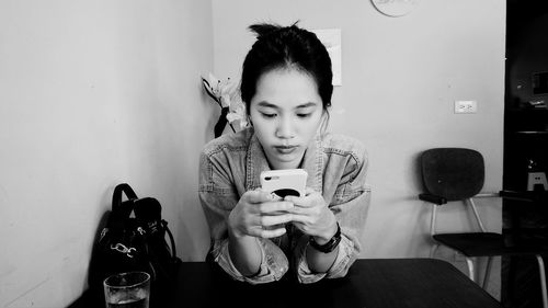 Young woman using mobile phone on table