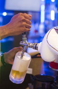 Cropped hands of bartender pouring beer in glass at bar
