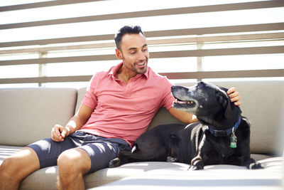 A man relaxing with his dog on an outdoor couch.