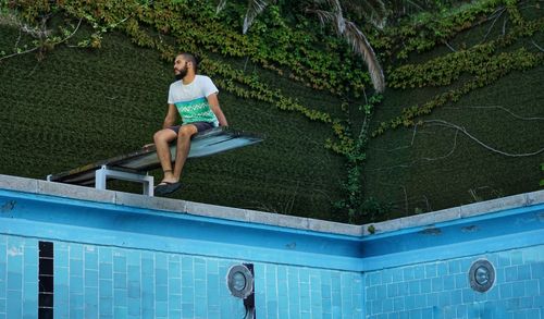 Full length of boy sitting on swimming pool