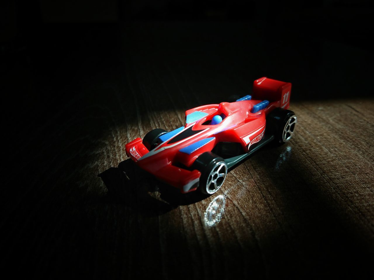 HIGH ANGLE VIEW OF TOY CAR ON TABLE AGAINST BLACK BACKGROUND