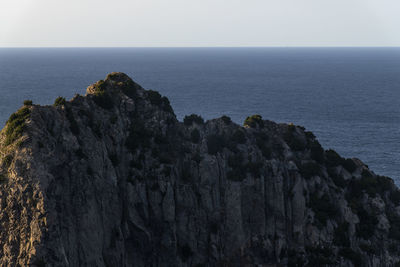 Rock formations by sea against clear sky