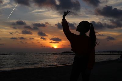 Silhouette man standing on beach against sky during sunset