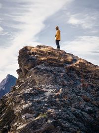 Man standing on rock by mountain against sky