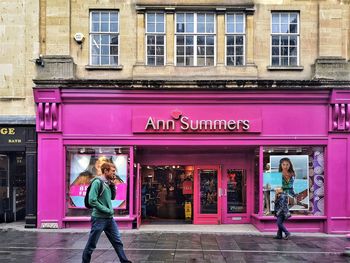 Full length of woman standing on street against building in city