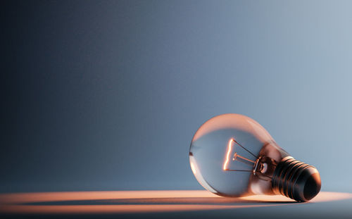 Close-up of illuminated light bulb on table